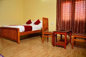 a bedroom with a bed with white sheets and red pillows at Redfox Villa - Kodaikanal in Kodaikānāl