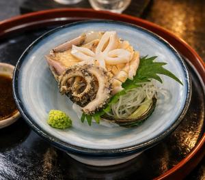 a plate of food with seafood on a table at Kappo Ryokan Kannawa Bettei in Beppu