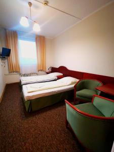 a hotel room with two beds and a chair at Dom Turysty Sanok in Sanok
