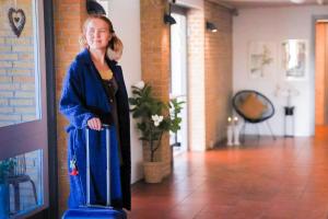 a woman standing in a hallway with a blue suitcase at Hotel Svanegården in Korsør