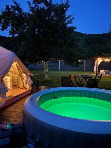 a large green pool next to a tent and a table at Green Garden Glamping Retezat in Bălan +33 photos