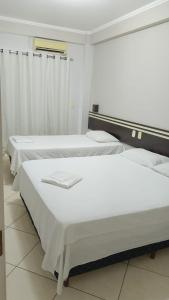 two beds in a room with white walls at Florença Hotel in Quedas do Iguacu