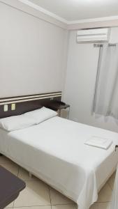 a white bed in a room with a window at Florença Hotel in Quedas do Iguacu +5 photos