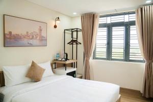 a bedroom with a white bed and a window at Black Win Hotel Phu Yen in Mỹ Hòa (1)