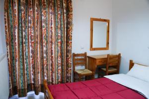 1 dormitorio con cama, escritorio y espejo en Elatos en Loutra Ipatis