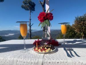 a plate of food on a table with two glasses at The Jungle Hook Binsar in Almora +82 photos