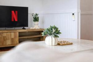 a living room with a table with a vase of flowers and a tv at 4 Bed Queenslander City Views Walk to Suncorp Deck + Parking in Brisbane