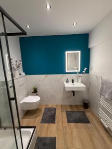 a bathroom with a blue wall and a toilet and a sink at Home&Living - Casa Nova in Meerbusch