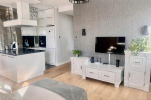 a kitchen with white cabinets and a flat screen tv at Apartament La Bella klimatyzacja, garaż podziemny, Fv in Suwałki