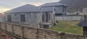 a house behind a stone wall with a building at Qax home in Qax