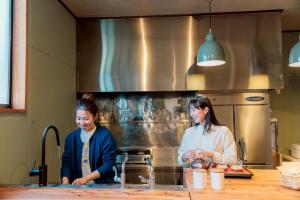 two women standing in a kitchen preparing food at めぐり宿 庵結 in Shimonoseki