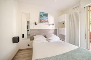 a white bedroom with a bed and a window at Appartement calme, clim, patio XXL, piscine&parking in Hyères