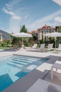 une piscine avec des chaises et des parasols blancs dans l'établissement Hotel Traube, à Bressanone
