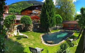 a backyard with a pool with chairs and a house at Pension Mayerhofer in Piesendorf