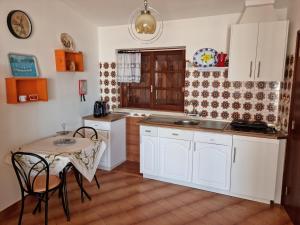 a kitchen with white cabinets and a table with chairs at Casa Nelinha by Rosado in Luz