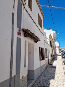 a white building on a street with a sidewalk at Casa Nelinha by Rosado in Luz