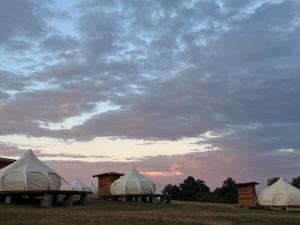 a group of tents in a field under a cloudy sky at Glamping Stolat in Stolat