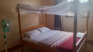 a bedroom with a wooden bed with a canopy at Palace Royal Hotel in Kagadi