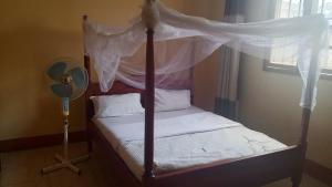 a bedroom with a canopy bed and a fan at Palace Royal Hotel in Kagadi