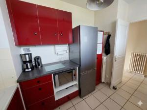 a kitchen with red cabinets and a stainless steel refrigerator at Le Cosy Gaillard 3 étoiles, magnifique vue sur la ville, parking privé et proche du centre in Brive-la-Gaillarde