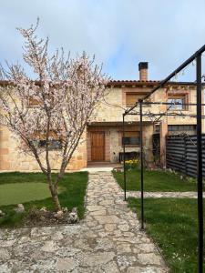 a tree in front of a house with a building at El Mirador de la Sierra Y Casa Rosmari in Urueñas