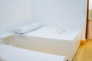 a white bed with white sheets and pillows on it at Quartz Suites in Camiguin