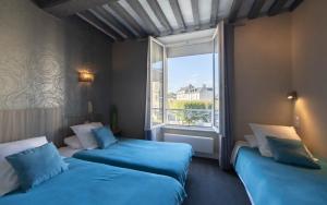 two beds in a room with a large window at Le Declic in Bayeux