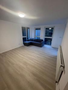 a living room with a black couch and some windows at Ferienapartments Sternen WOHN 6 in Baiersbronn