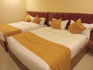 two beds in a hotel room with yellow pillows at Siddi Vinayaka hotel in Hyderabad