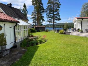 a yard with a house and a lake in the background at Brinken 3 in Sörberge