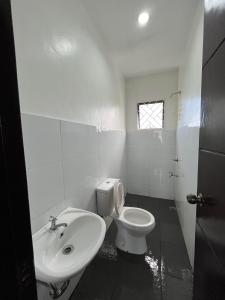 a white bathroom with a toilet and a sink at Casa Flores in Sampong +24 photos