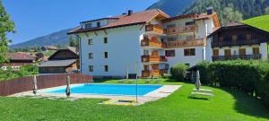 a large building with a swimming pool in front of it at Hotel Pichlerhof in San Lorenzo di Sebato
