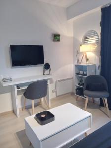 a living room with a desk with a tv and two chairs at Résidence Le poisson d'or in Perros-Guirec