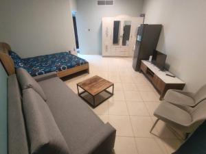 a living room with a couch and a tv at Trendy Studio In Orient Towers Ajman in Ajman 