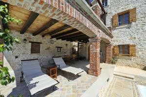 an outdoor patio with two lounge chairs and a brick building at Villa Gland in Nin