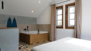 a bedroom with a tub and a bed and a window at Avala apartments in Beli Potok
