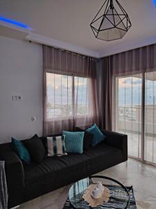 a living room with a black couch and some windows at Bizerte appartement in Bizerte