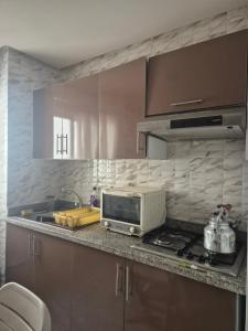 a kitchen with a microwave and a stove top oven at Residence les jardins cap de l eau in Ras El Ma