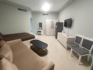 a large living room with a couch and a tv at Cozy Studio In Orient Towers Ajman in Ajman 