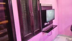 a tv and a window in a pink room at Hotel rishav prime in Ghaziabad