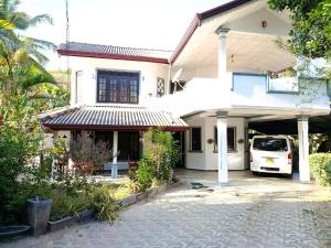 a white house with a car parked in the driveway at Zion Haven Villa in Tangalle