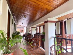 a porch with chairs and tables and a wooden ceiling at Golden Sun Hotel Luang Prabang in Luang Prabang