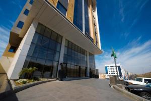 a building with large windows and a parking lot at Grand Iva Hotel Abha in Abha