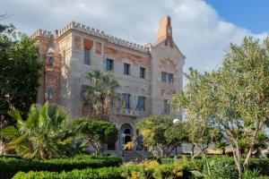 a building with a palm tree in front of it at Agorà di Favignana - Affittacamere Piazza Madrice in Favignana