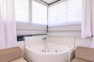 a white bath tub in a bathroom with a window at האלפים של הכרמל ומצפה העמקים- וילה ומלונית מול נוף הצפון in Talpiyyot +23 photos