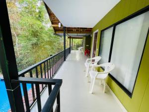 a balcony of a house with white chairs at Stillora Hotel And Resorts in Sultan Bathery
