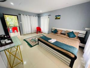 a bedroom with a bed and a table and red chairs at Stillora Hotel And Resorts in Sultan Bathery