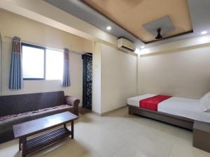 a bedroom with a bed and a couch and a window at Hotel Krantiveer in Kālundri