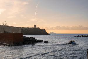 a couple in the water with a lighthouse in the background at De Sanctis-Apartment in Piombino