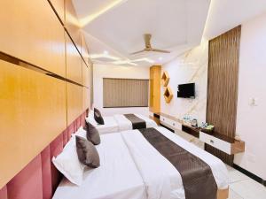 a hotel room with two beds and a tv at Hotel Hira Palace in Ujjain